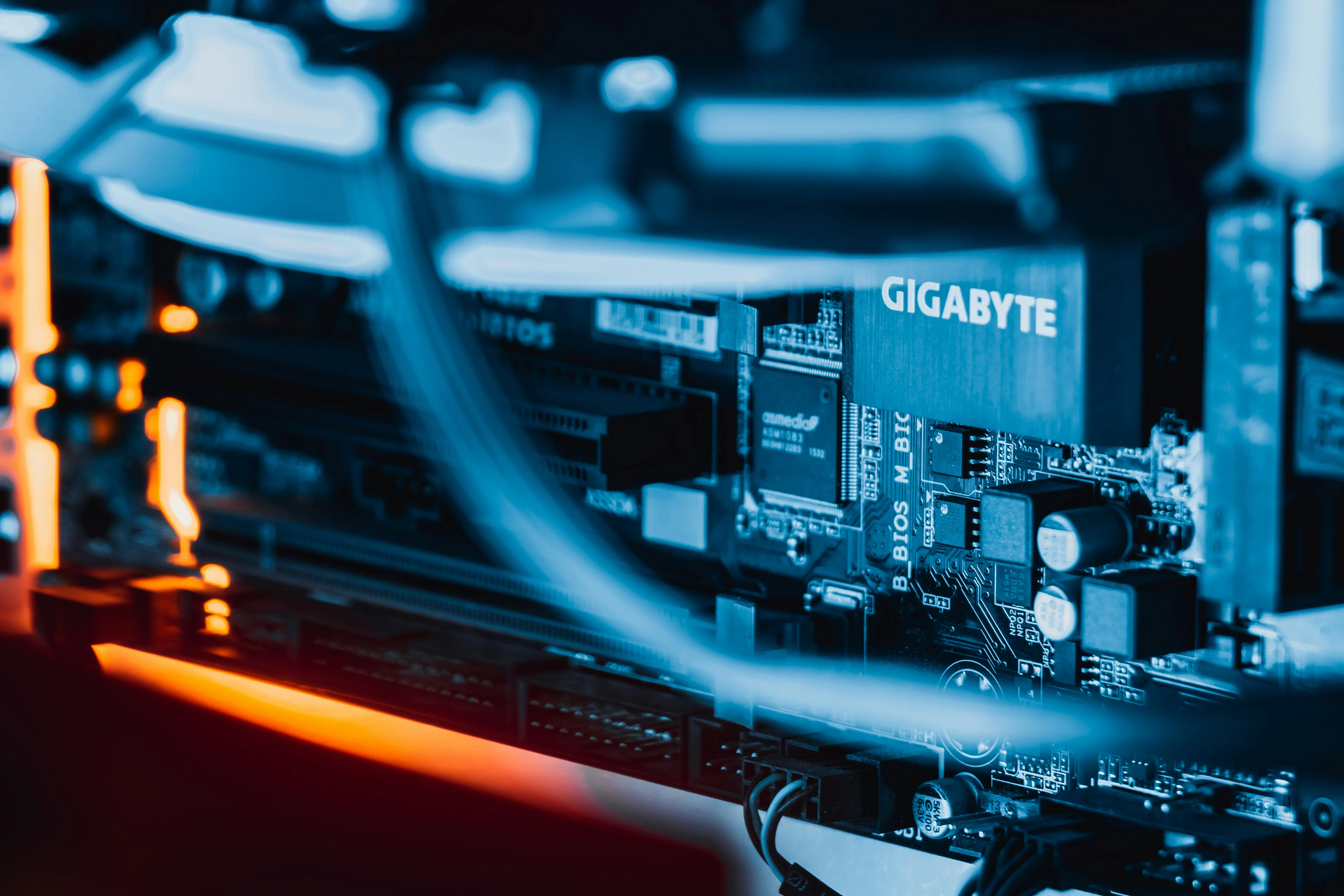 Close-up of a blue-lit computer motherboard with visible BIOS chips and orange LED reflections